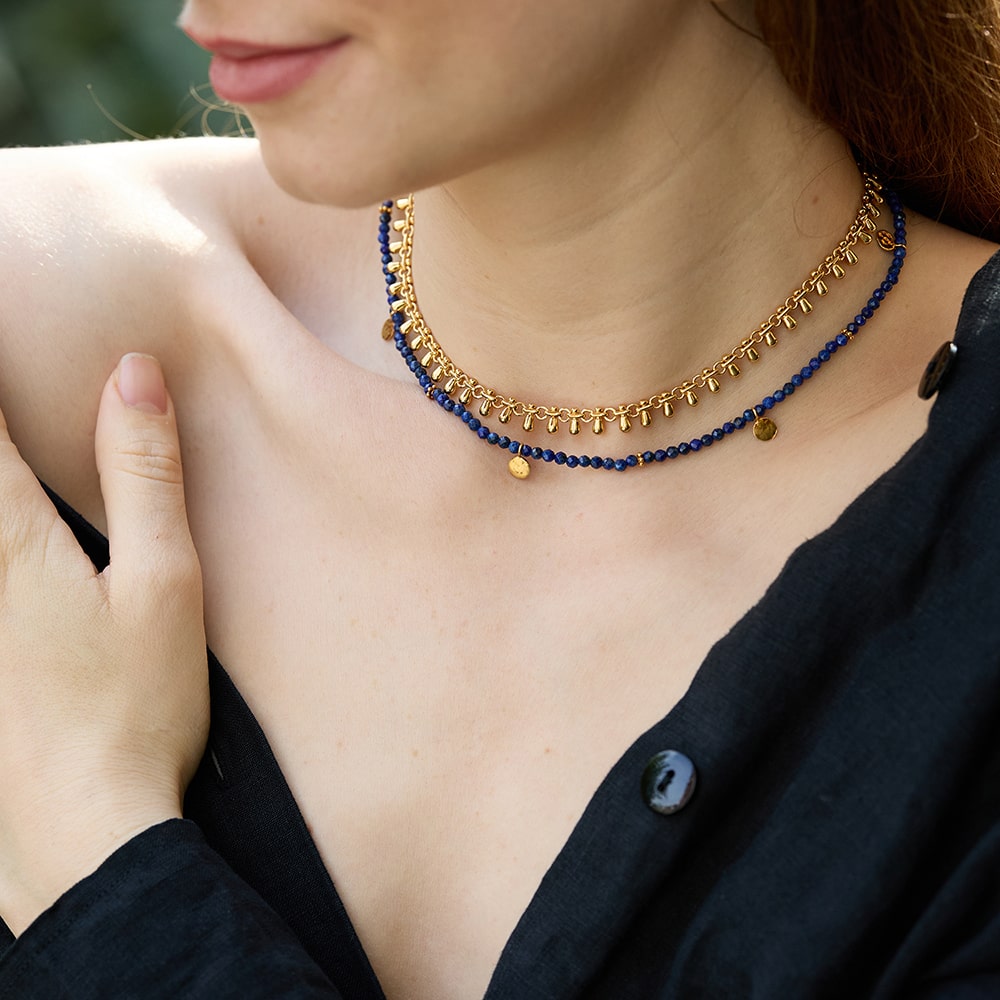 Handmade using sustainable materials, the Eva Lapis Lazuli Reversible Necklace with gold discs radiates shades of blue and gold from its vintage gemstones. Reverse the necklace for a smooth gold look or embossed texture on the charms.