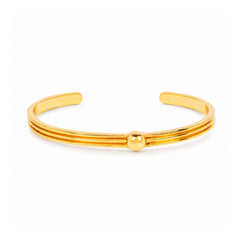 A polished gold-tone metal cuff bracelet with three parallel bands and a small central bead, shown on a clean white background.