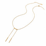 A gold Y-shaped necklace with a delicate chain, a small curved bar at the center, and two thin drop chains ending in cylindrical pendants, shown on a plain white background.