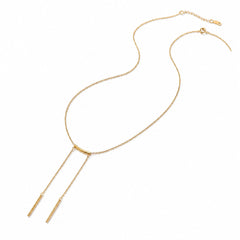 A gold Y-shaped necklace with a delicate chain, a small curved bar at the center, and two thin drop chains ending in cylindrical pendants, shown on a plain white background.