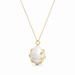 A gold chain necklace featuring a large, teardrop-shaped white mother-of-pearl pendant adorned with small gold studs, shown against a plain white background.