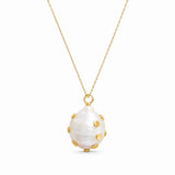 A gold chain necklace featuring a large, teardrop-shaped white mother-of-pearl pendant adorned with small gold studs, shown against a plain white background.