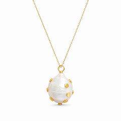 A gold chain necklace featuring a large, teardrop-shaped white mother-of-pearl pendant adorned with small gold studs, shown against a plain white background.