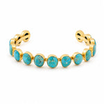 A gold cuff bracelet featuring a row of oval turquoise stones, set against a clean white background.