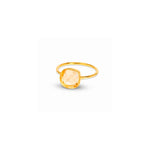 A gold ring featuring a large, cushion-cut pale peach crystal, shown on a plain white background with a soft shadow.