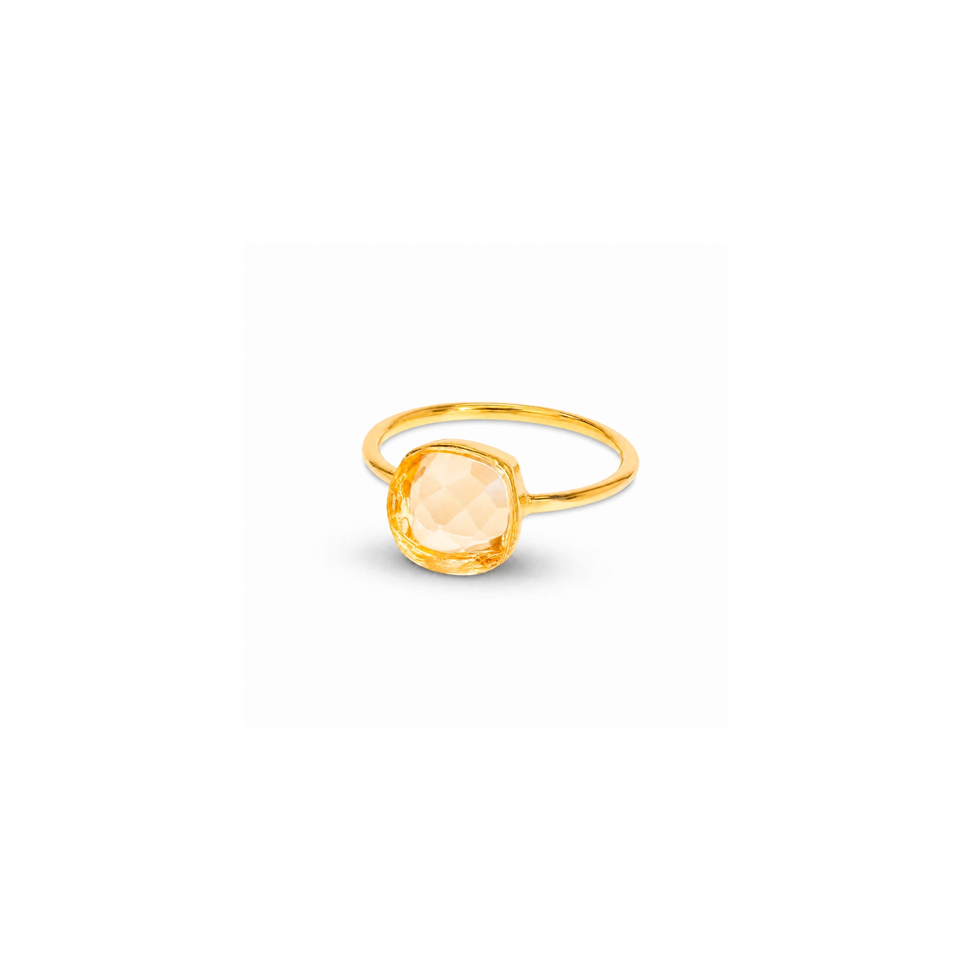 A gold ring featuring a large, cushion-cut pale peach crystal, shown on a plain white background with a soft shadow.