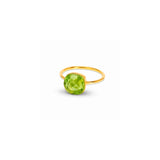 A yellow gold ring featuring a round, faceted green gemstone, shown on a plain white background with a soft shadow.