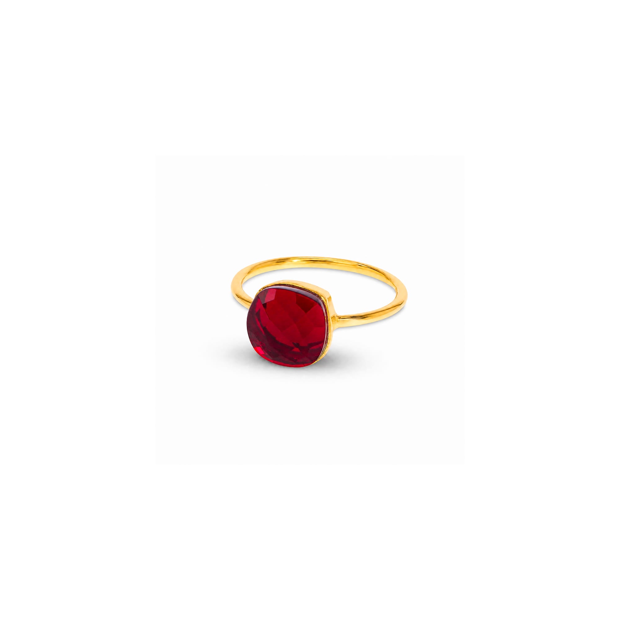 A gold ring with a cushion-cut red gemstone, shown on a plain white background with a soft shadow.