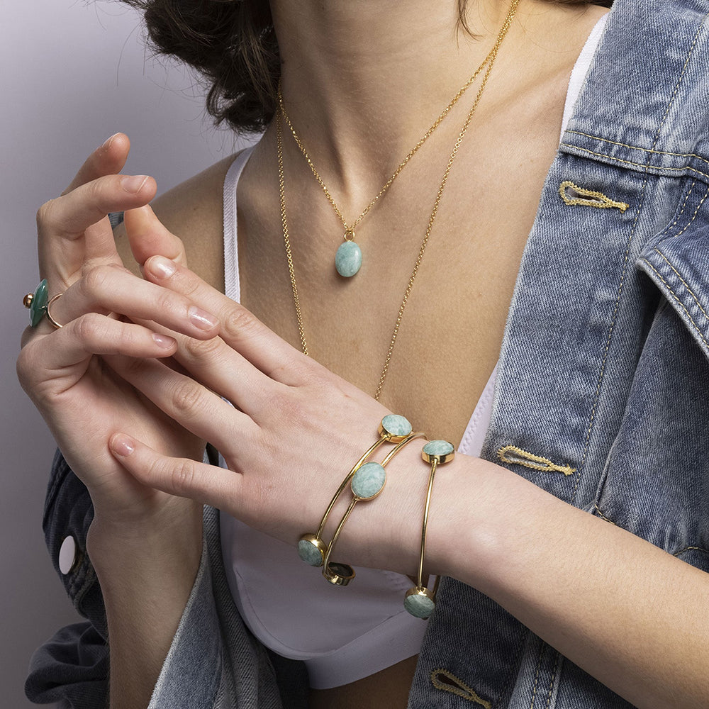 Our Sasha Gold Bangle With Amazonite Gemstones is handmade with recycled materials for minimal environmental impact. Adorned with three stunning vintage Amazonite gemstones, this bangle catches the light with your every move.